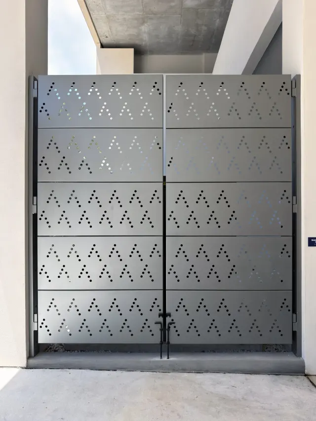 Perforated aluminum service gates matching the Art House façade pattern.
